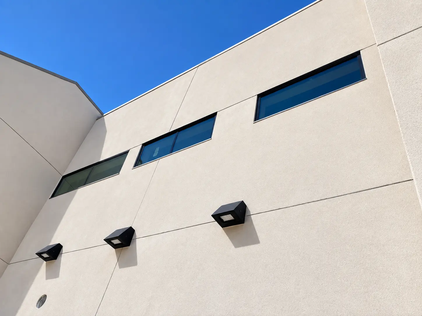 Facade detail of the medical office — stucco control joints, ribbon windows, and wall lights