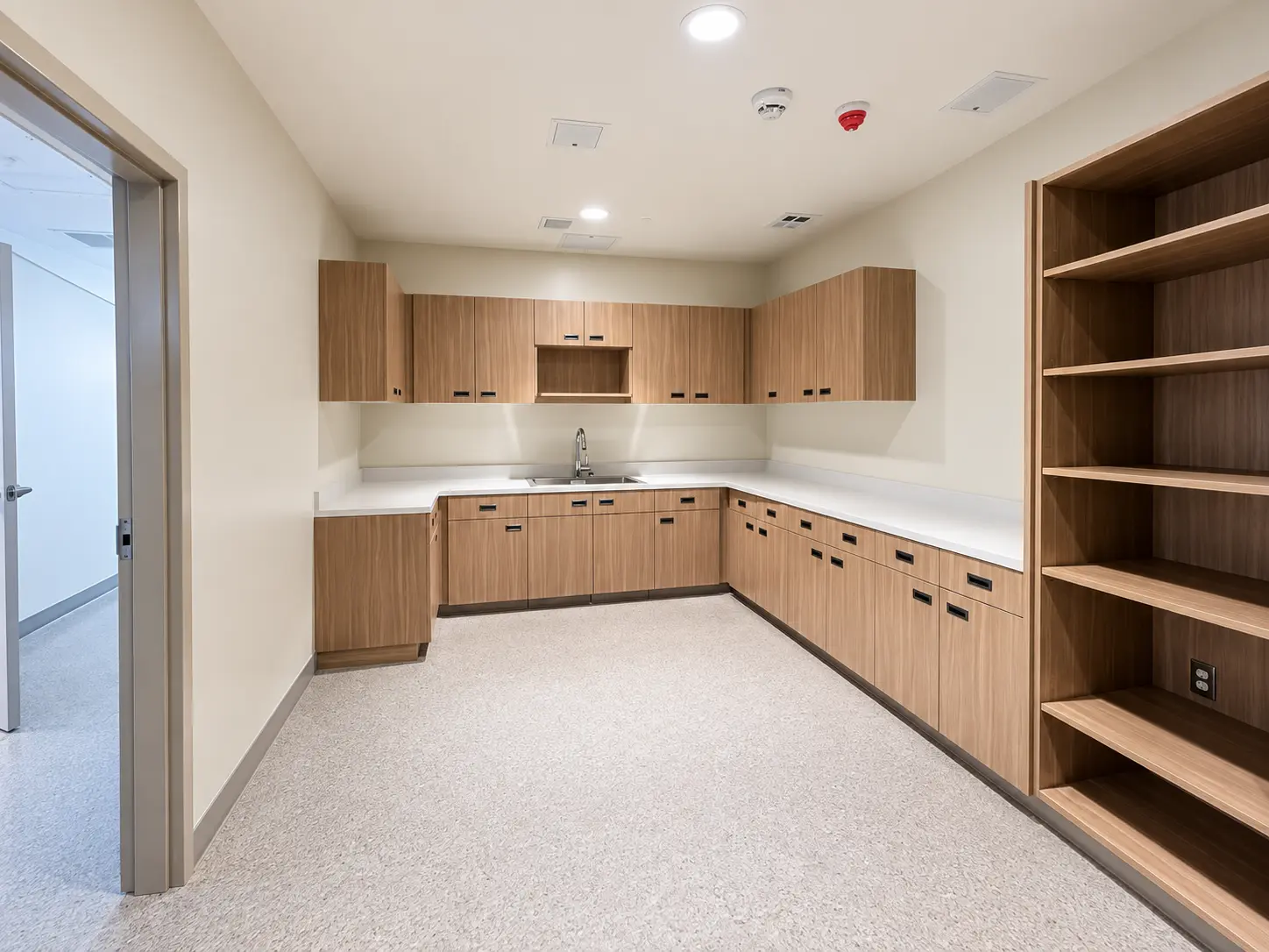 Staff kitchenette with wood-tone cabinetry and open shelving