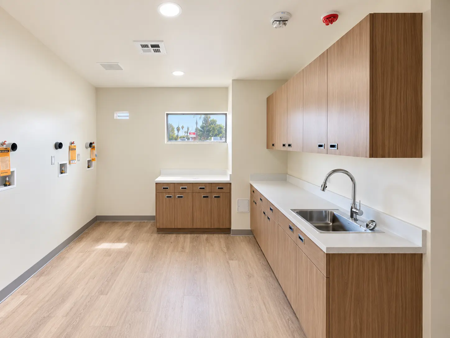 Work room with wood cabinetry, sink, and utility connections